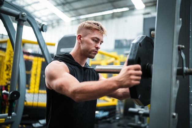 Male athlete exercising in the gym lifting weights pulling joints