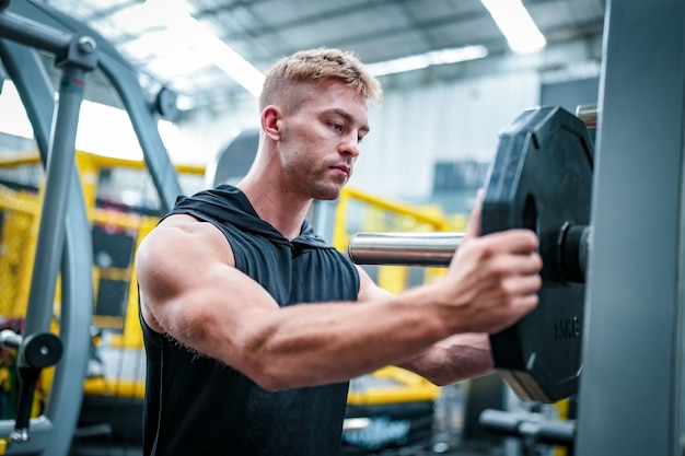 Male athlete exercising in the gym lifting weights pulling joints