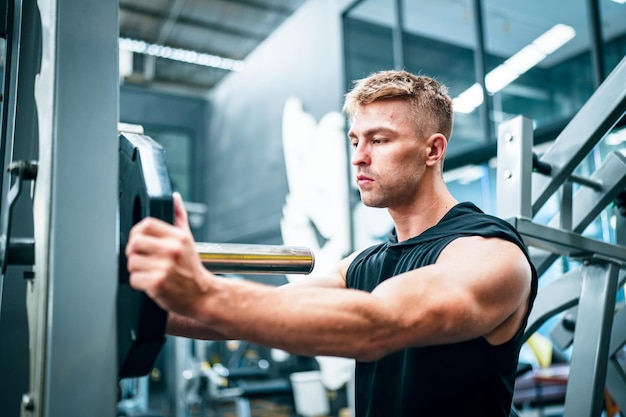 Male athlete exercising in the gym lifting weights pulling joints