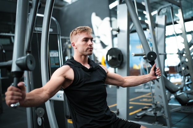 Male athlete exercising in the gym lifting weights pulling joints