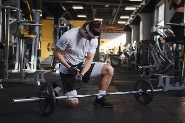 Male athlete preparing for barbell workout wearing weightlifting belt