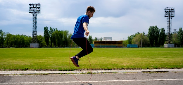 Male athlete sportsman practice with jump rope at the outdoor stadiums, increase stamina