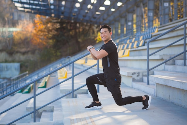 Male athlete trains in a backpack asian fitness performs exercises outside the stadium in the morning