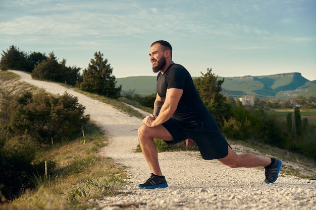 Male athlete warming up before start running in mountains