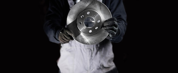 Male auto mechanic holding a new brake disc, car brake system concept.