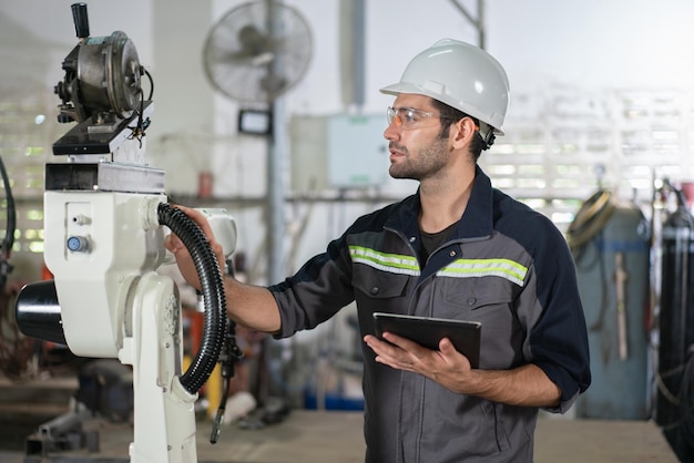 Male automation engineer checking and inspection control a robot arm welding in industrial factory