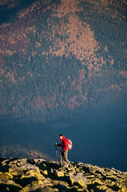 Male backpaker walking on the rocky top of the mountain