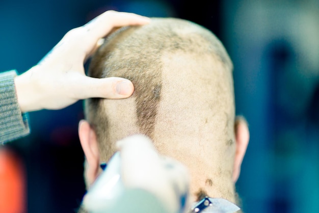 A male barber is shaving the back of male's neck