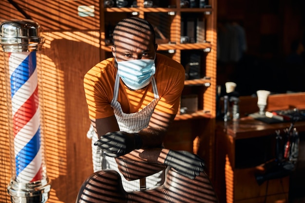 Male barber in medical mask standing in barbershop