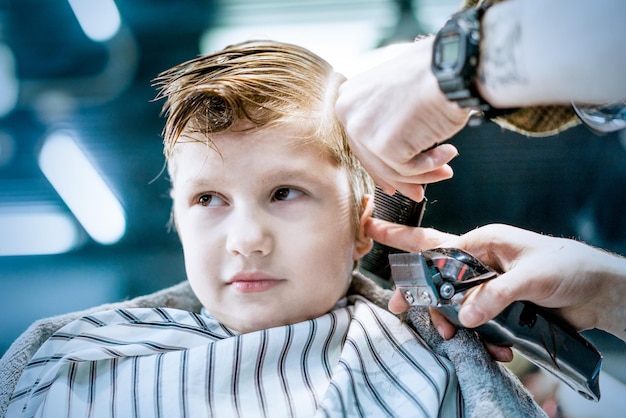 A male barber's hand trimming boys hair