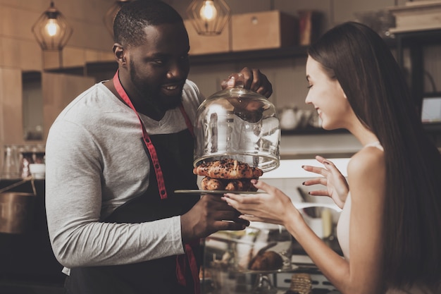 Male barista helps a girl to choose a dessert