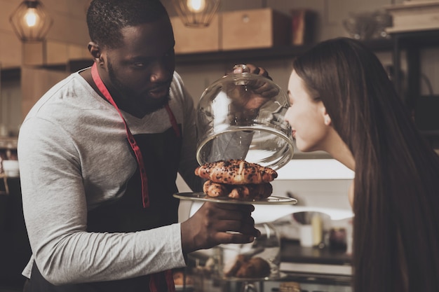 Male barista helps a girl to choose a dessert