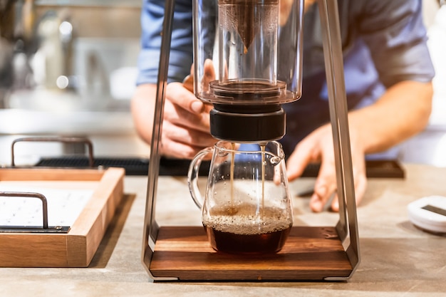 Photo male barista making pour-over coffee with alternative method called dripping.