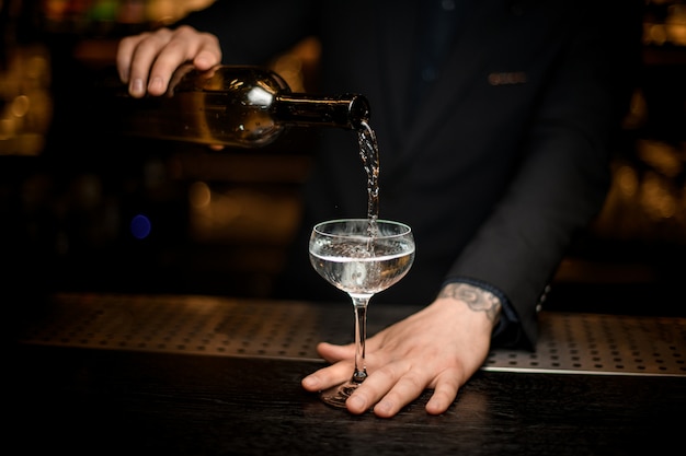 Male bartender adds champagne in a glass