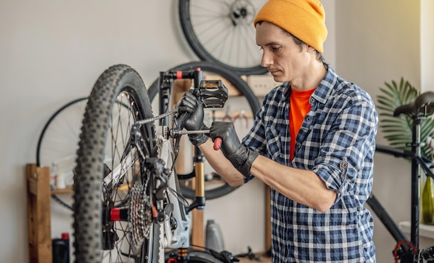 Photo a male bicycle mechanic repairs a mountain bike in a workshop