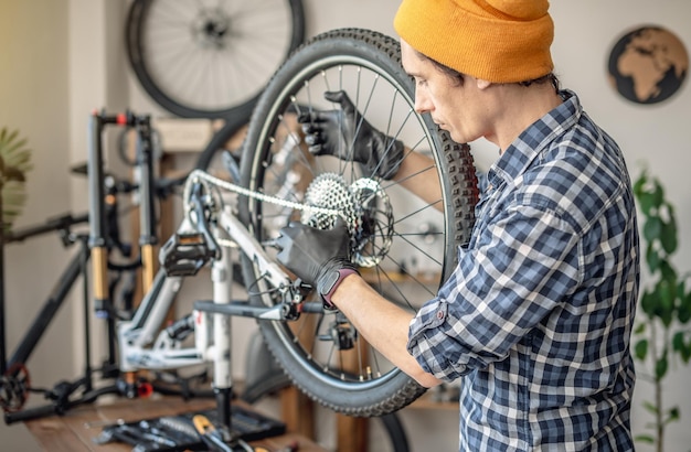 Photo a male bicycle mechanic in the workshop disassembles a mountain bike and repairs it