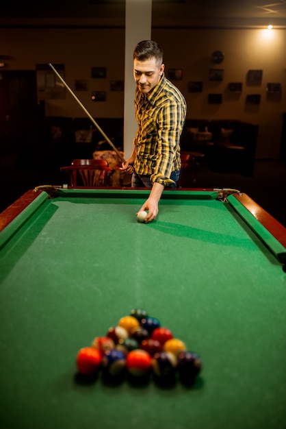 Male billiard player with cue aiming at the table