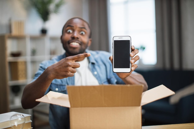 Male blogger opening parcel with new smartphone