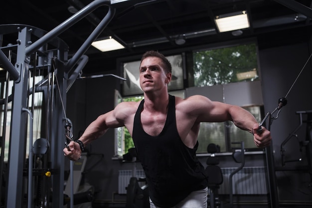 Male bodybuilder looking focused doing chest exercise in cable crossover