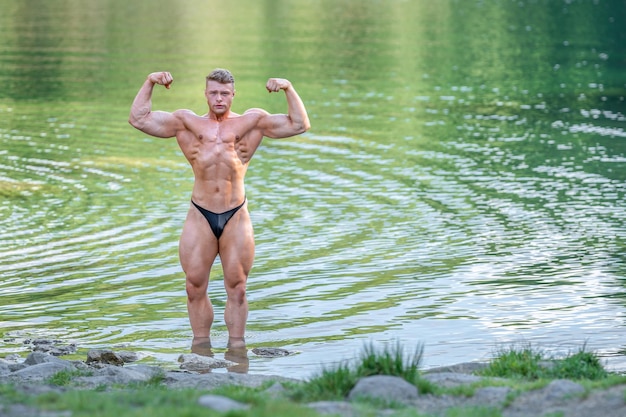 Male bodybuilder in the water in nature