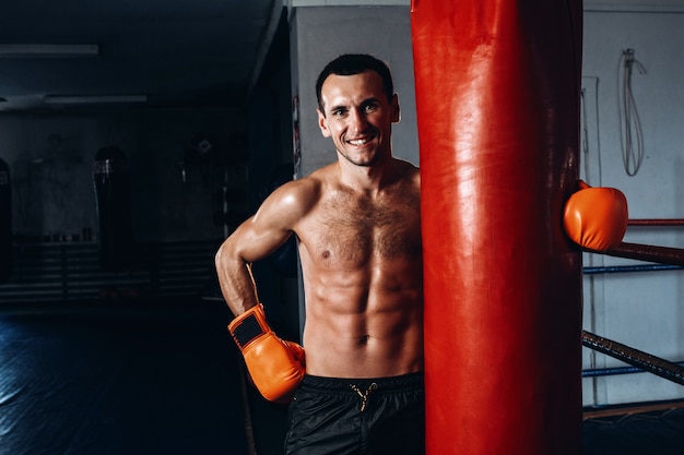 Male boxer training in dark gym.