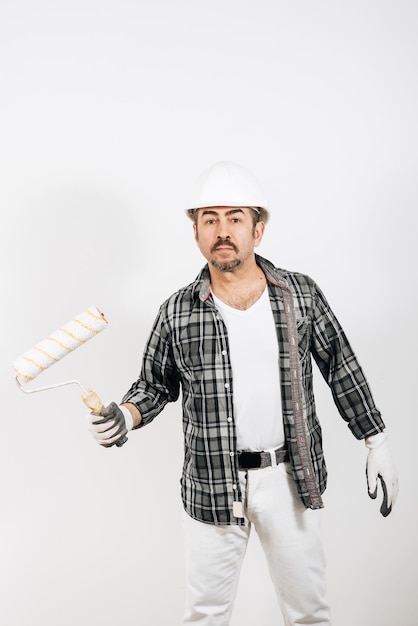 Male builder in a hard hat holding a paint roller on a white background