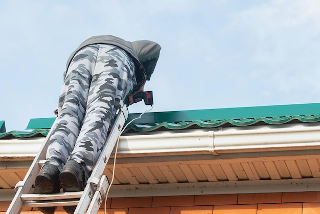 male builder installs snow guards on the roof of the house