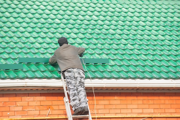 male builder installs snow guards on the roof of the house