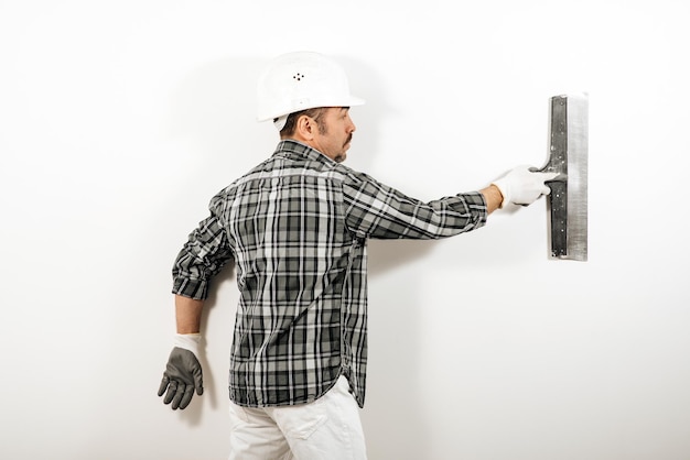 Male builder plastering a white wall