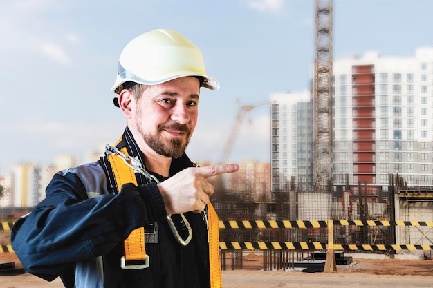 A male builder in a white hard hat against a blurred background of a construction site with a blue sky Positive civil engineer with a beard