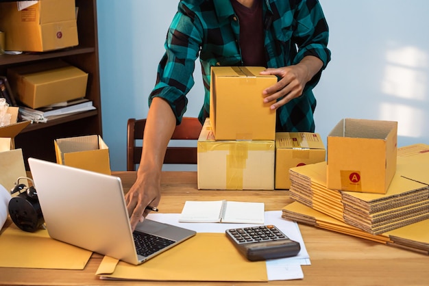 male business owner working packing the order for shipping to customer working with laptop