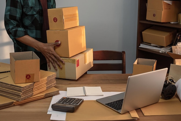 Male business owner working packing the order for shipping to customer working with laptop