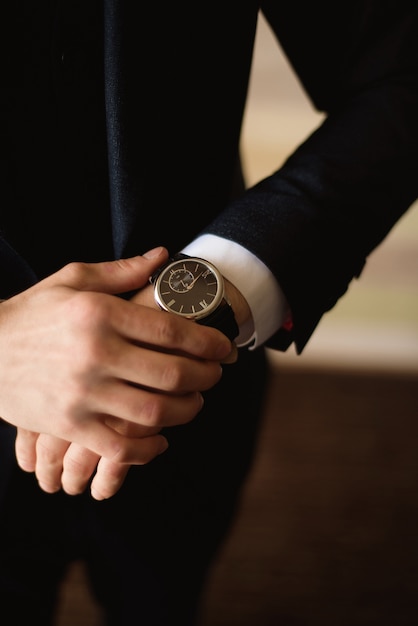 Male businessman dresses and adjusts his watch, preparing for a meeting. Clock