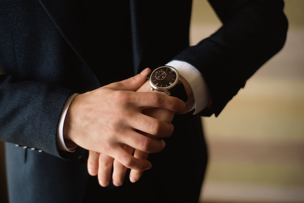 Male businessman dresses and adjusts his watch, preparing for a meeting. Clock