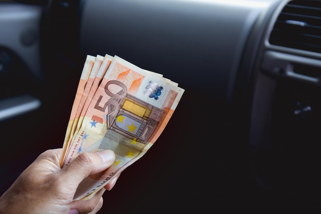 A male businessman pays taxi fare in euros with a tip for excellent service Business concept