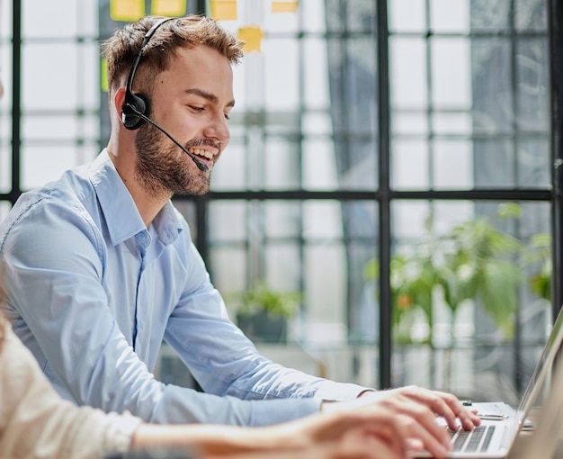 Male callcenter operator with headphones sitting at modern office