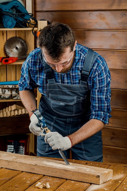 Male carpenter hammers wood with a chisel carpentry tools