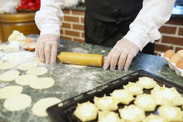 Male chef uses ingredients for preparing flour products on the kitchen table