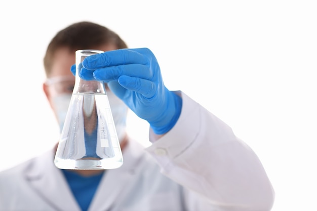 A male chemist holds test tube of glass in his hand overflows a liquid solution of potassium permanganate