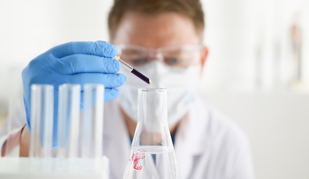 A male chemist holds test tube of glass