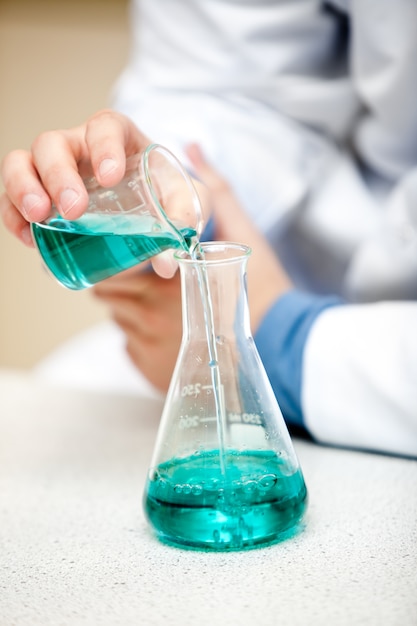 Male chemist pouring a blue liquid