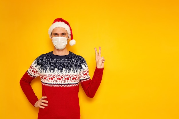 Photo male in christmas sweater with reindeer shows sign v victory peace isolated yellow background