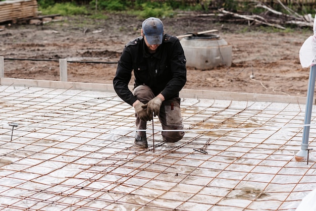 Male construction worker prepares rebar for the foundation of the construction of a house for pouring concrete