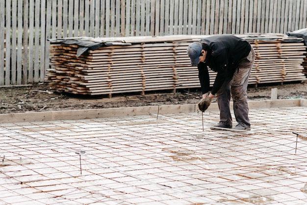 Male construction worker prepares rebar for the foundation of the construction of a house for pouring concrete