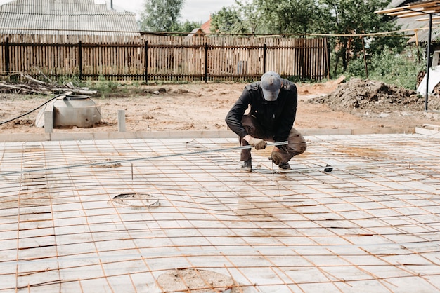 male construction worker prepares rebar for foundation of construction of house and pouring concrete