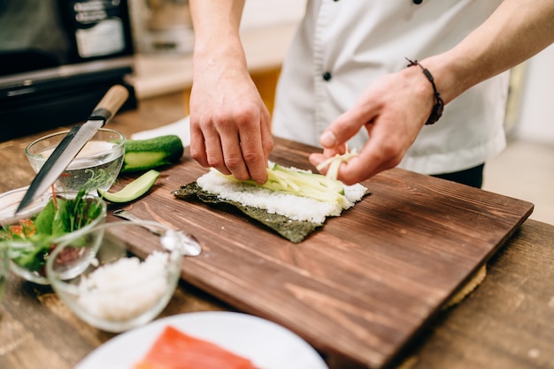 Male cook hands making sushi rolls