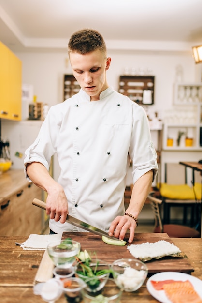 Male cook making sushi rolls on the kitchen. Traditional japanese food, preparation process, seafood