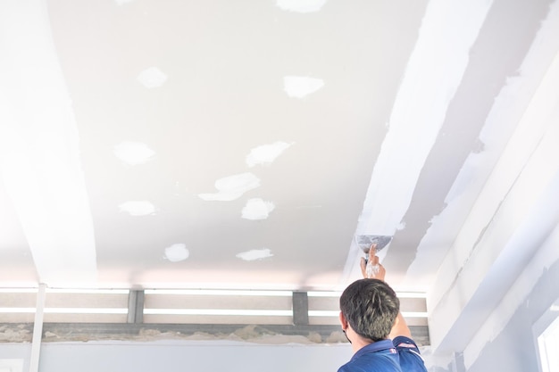 Male craftsman is using a white lantern to make ceilings in the house build a house decorate the interior of the house