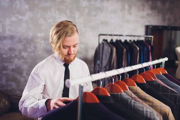 Male customer looking for a jacket in men clothes store.