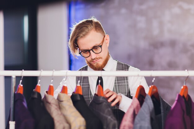 Male customer looking for a jacket in men clothes store.